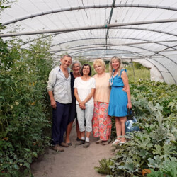 Araik Serobyan, des bénévoles et Mme Hattat de L'Epicerie Sociale en visite à L'Ecole des Jardiniers en 2022 (Photo T. Herve) 5 personnes posant au milieu des cultures sous une serre